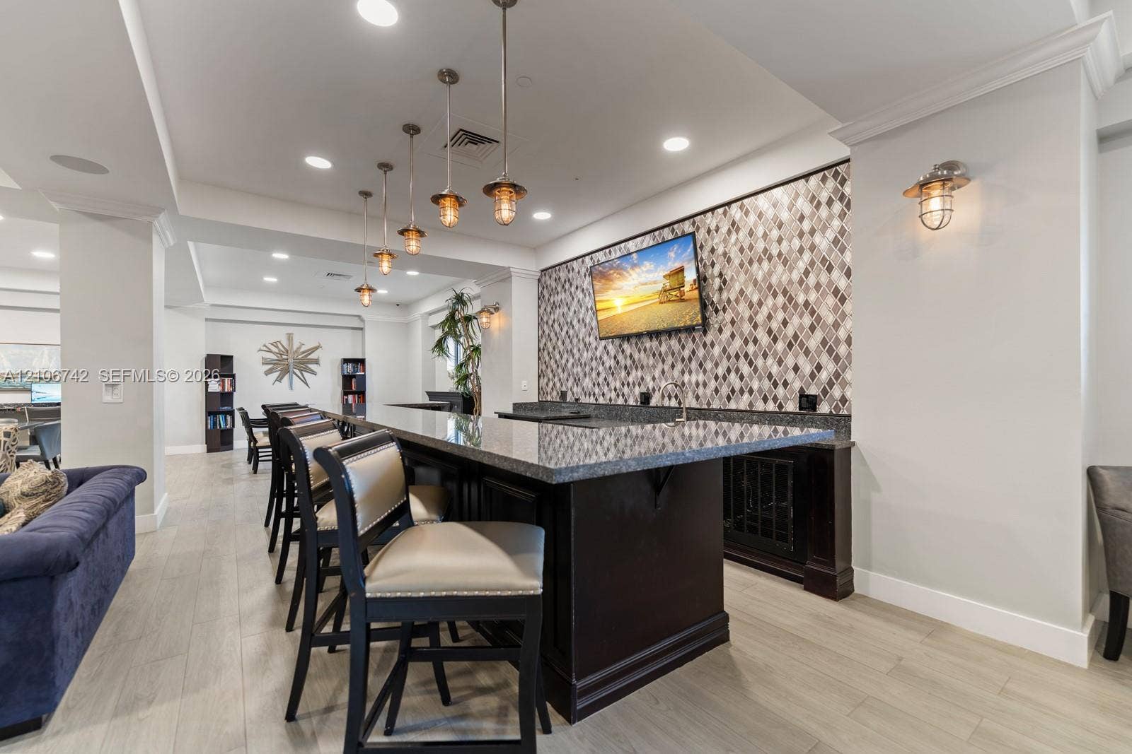 Built-in wet bar featuring stone-finish countertops, geometric tile backsplash, recessed lighting, and pendant fixtures