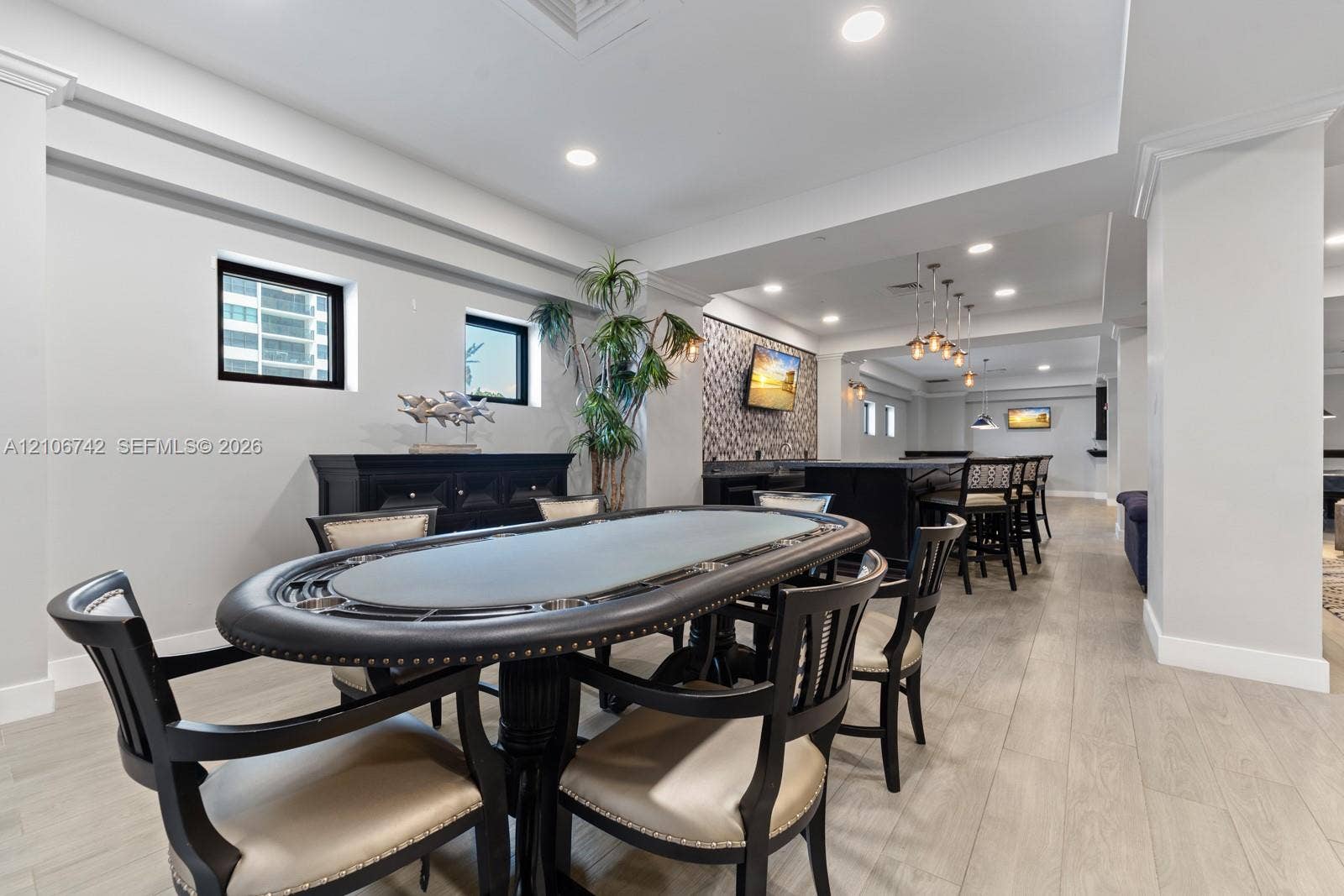 Common area featuring wood-finish flooring, recessed lighting, a built-in wet bar with dark cabinetry, patterned stone-tiled backsplash, and multi-pendant illumination