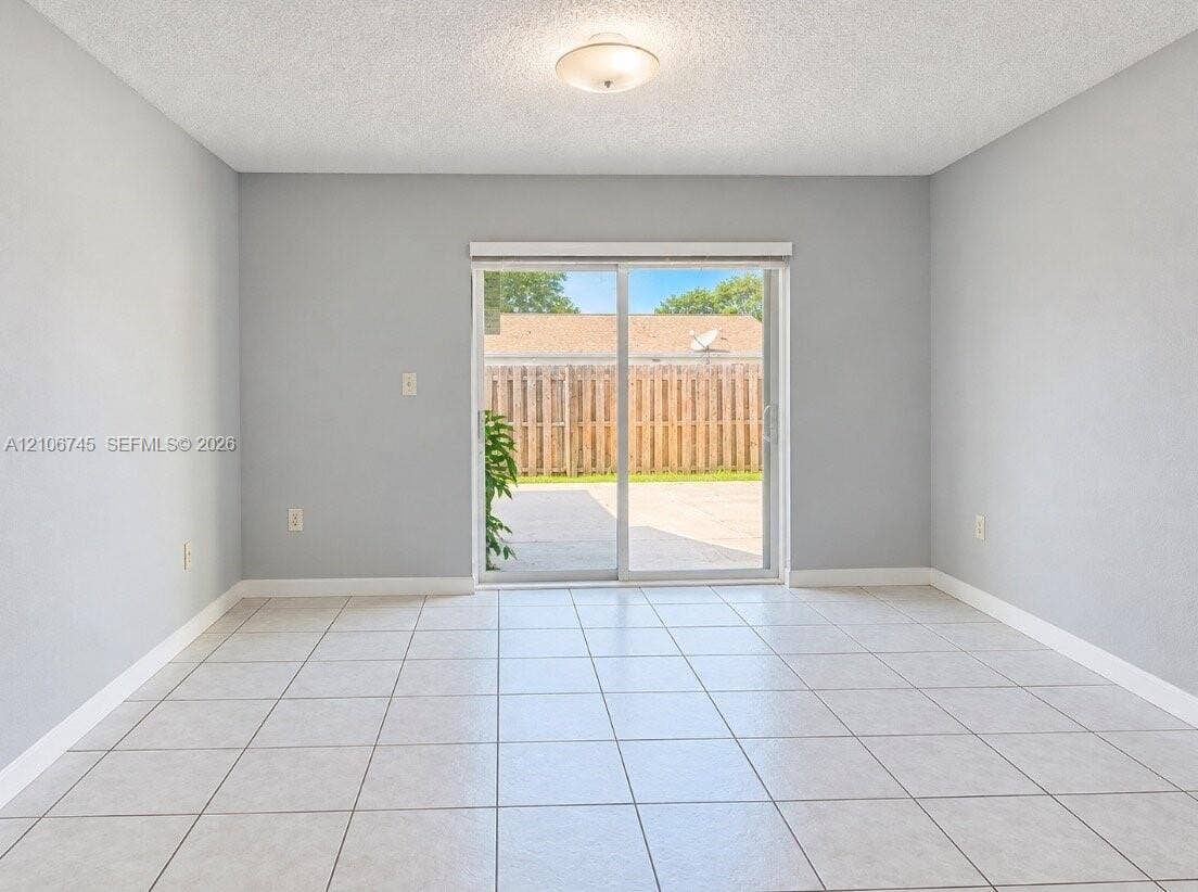 14658 SW 126th Place, Miami, FL 33186 Neutral-toned interior featuring large-format ceramic tile flooring, sliding glass patio door, and flush-mount ceiling lighting