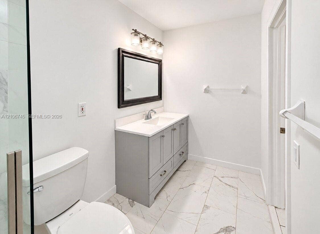 14658 SW 126th Place, Miami, FL 33186 Bathroom featuring a gray vanity with an integrated countertop and basin, large-format tile flooring, a framed wall mirror, and a glass-enclosed shower