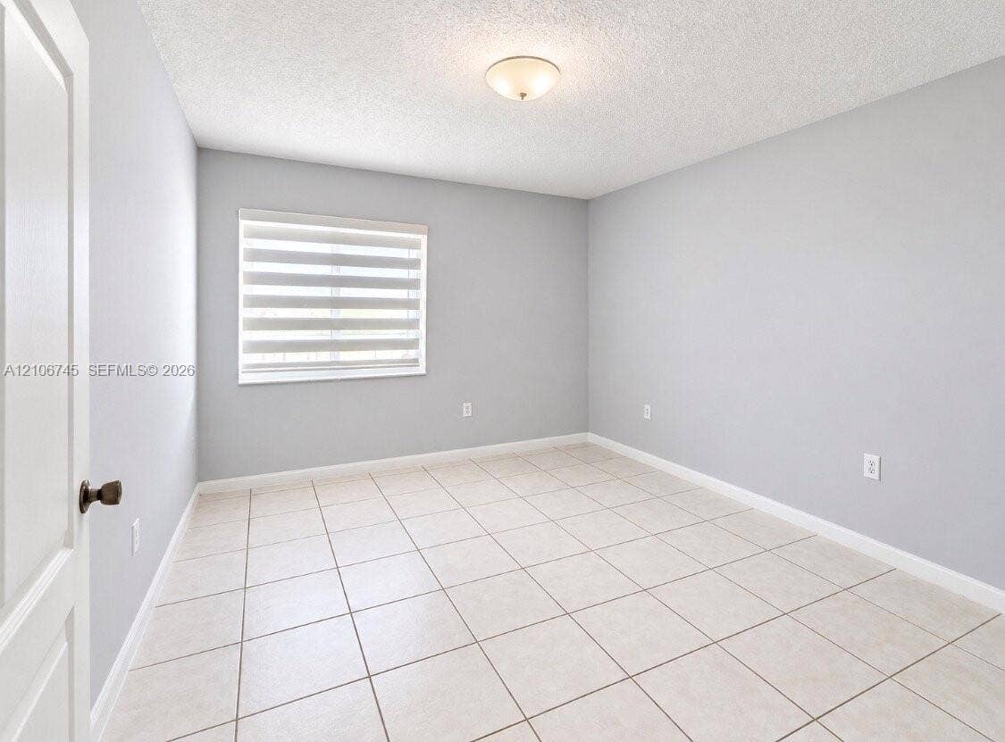 14658 SW 126th Place, Miami, FL 33186 Neutral-toned interior space featuring tile flooring, a window with installed roller shades, and a ceiling-mounted dome light fixture