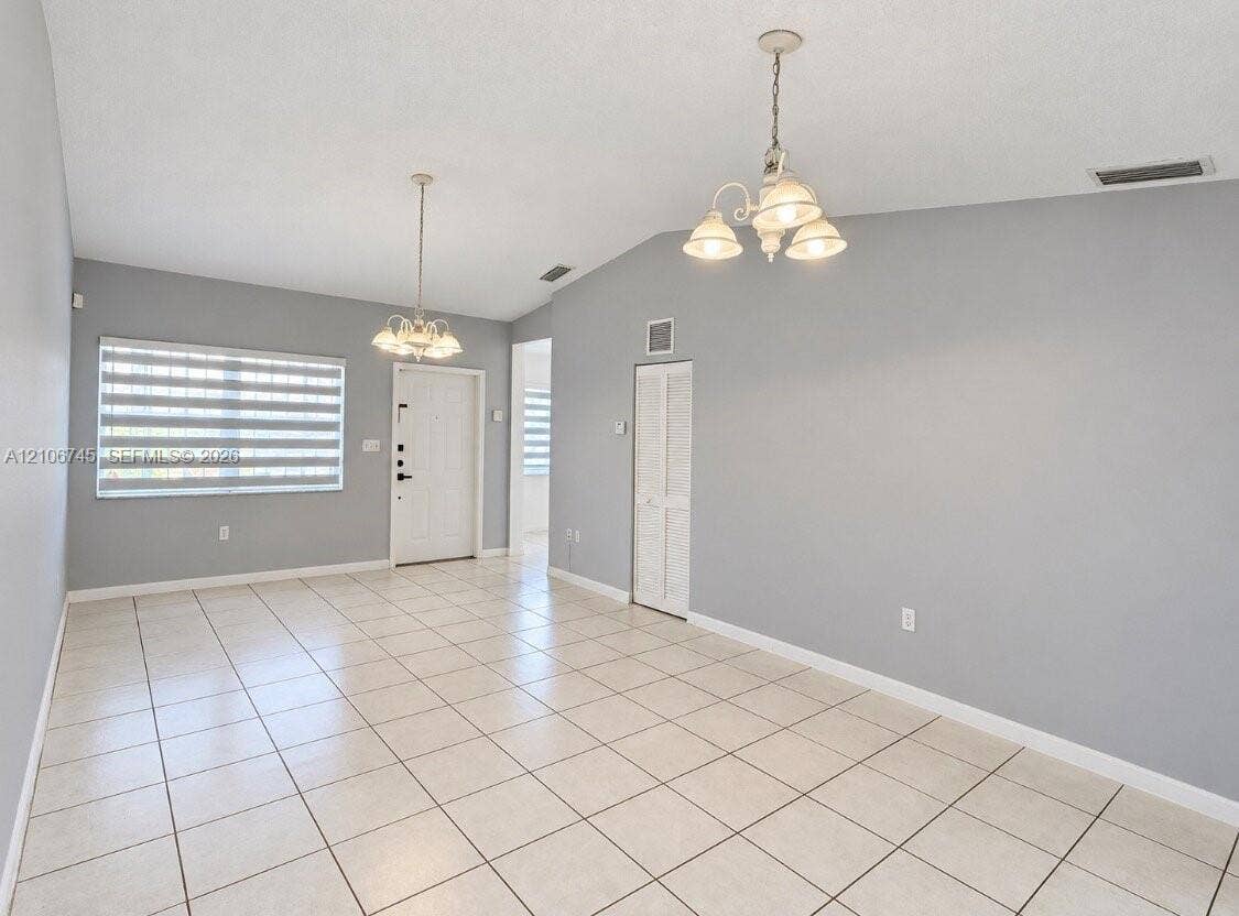 14658 SW 126th Place, Miami, FL 33186 Open interior featuring high vaulted ceilings, large-format tile flooring, dual multi-arm chandeliers, and crisp neutral wall tones