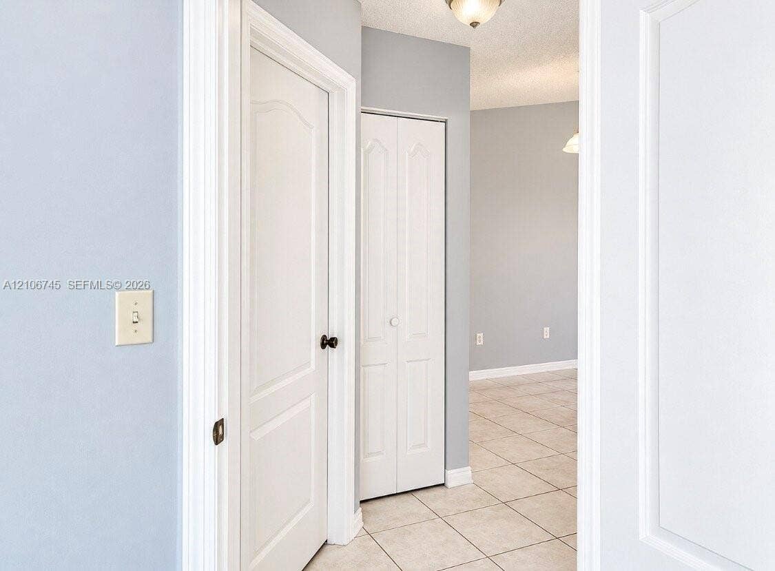 14658 SW 126th Place, Miami, FL 33186 Neutral wall tones featuring white interior doors with arched-top panels, tile flooring, and bi-fold closet doors