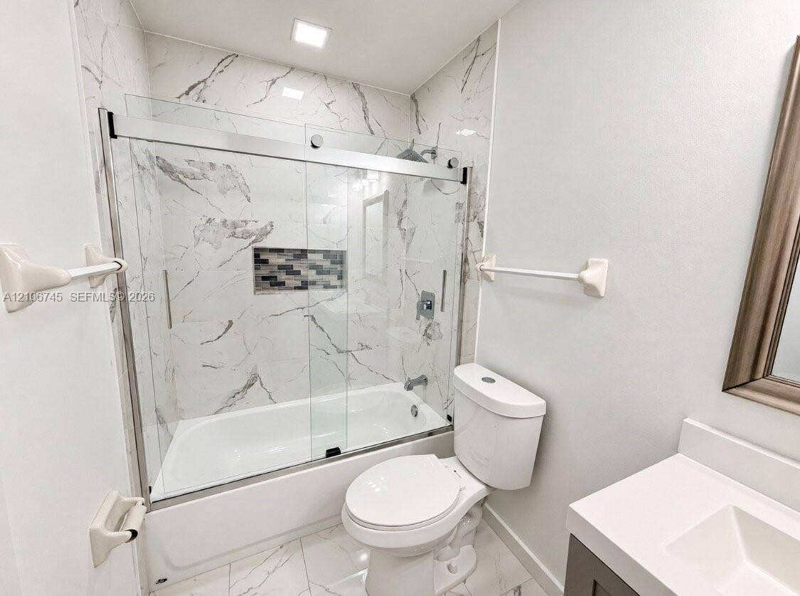 14658 SW 126th Place, Miami, FL 33186 Full-height shower surround with veined tile, sliding glass shower door, integrated wall niche, and vanity with stone-style countertop