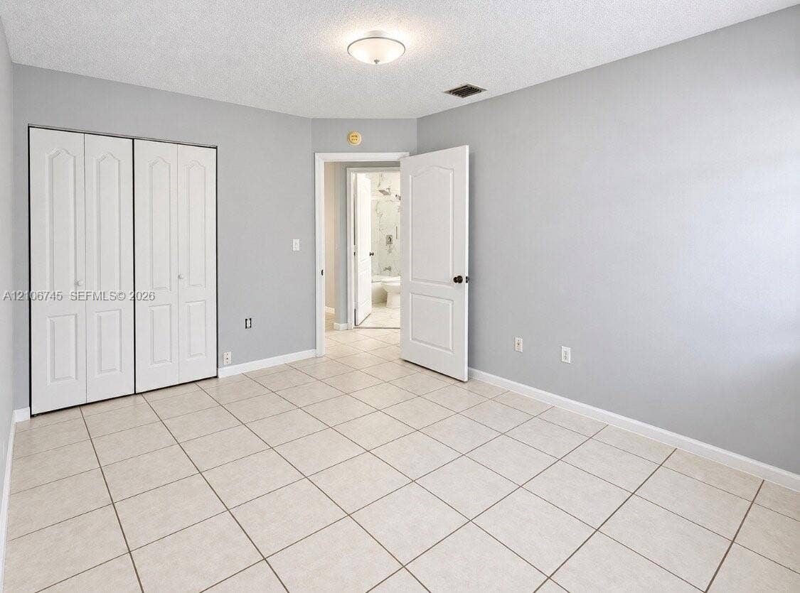 14658 SW 126th Place, Miami, FL 33186 Neutral interior featuring light-toned tile flooring, white bi-fold closet doors, a neutral wall color palette, and a semi-flush mount ceiling fixture