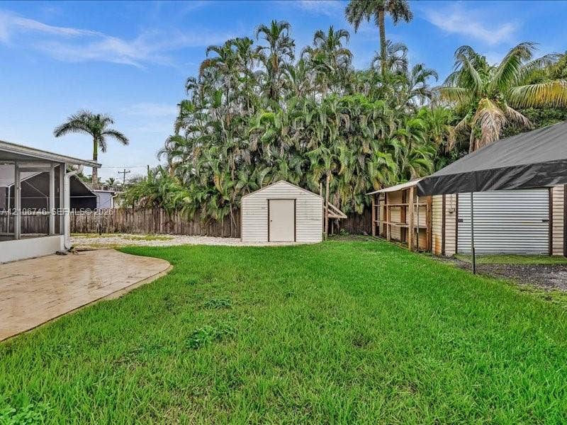 6608 SW 49th Street, #0, Davie, Davie, FL 33314 Spacious backyard featuring a concrete patio, detached storage shed, metal-roofed structure, and perimeter fencing