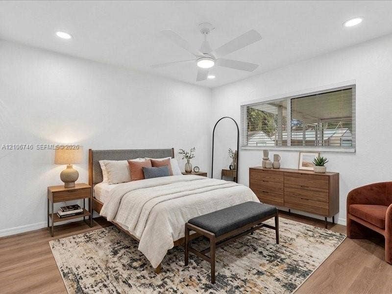 Neutral-toned room featuring wood-finish flooring, recessed lighting, a white ceiling fan with integrated light, and a large window