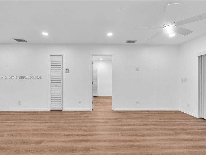 Neutral interior space featuring wood-finish flooring, recessed lighting, a white ceiling fan, and a louvered closet door