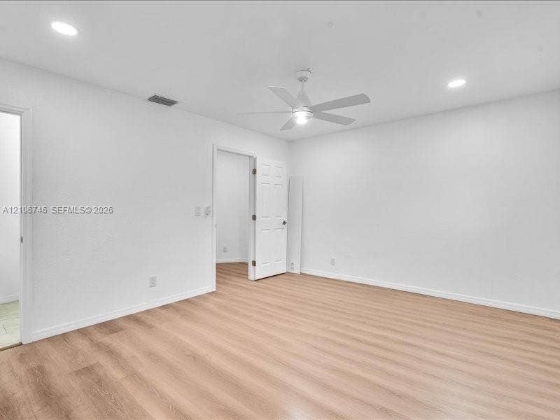 Neutral-toned wood-finish flooring, recessed lighting, and a white ceiling fan with integrated light fixture