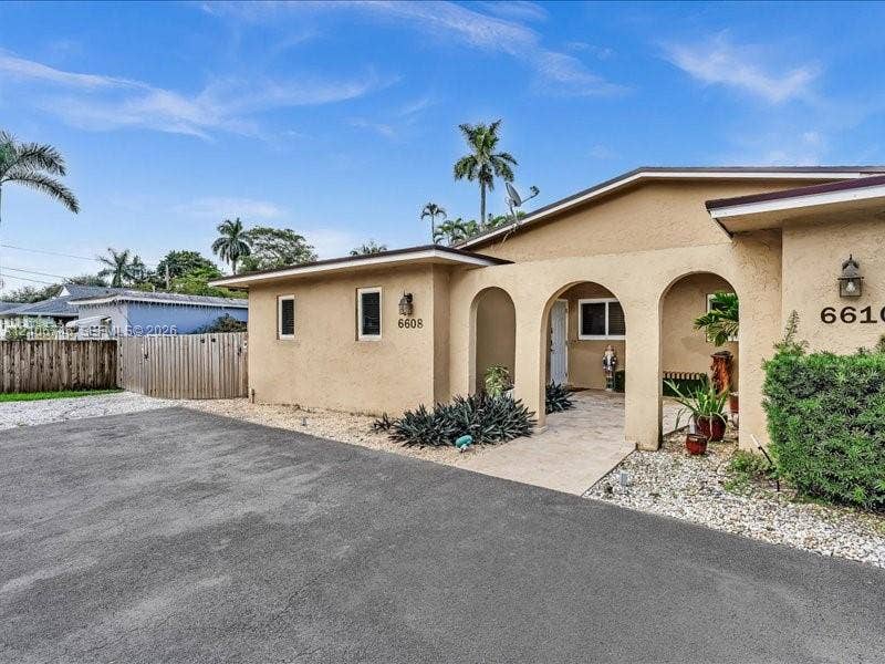 6608 SW 49th Street, #0, Davie, Davie, FL 33314 Stucco exterior featuring dual arched entryways, a paved driveway, and decorative exterior wall-mounted lighting