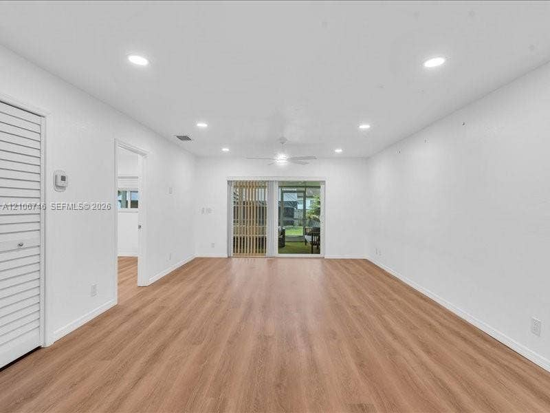 Spacious room featuring wood-finish flooring, recessed lighting, a ceiling fan, and sliding glass doors leading to an enclosed outdoor area