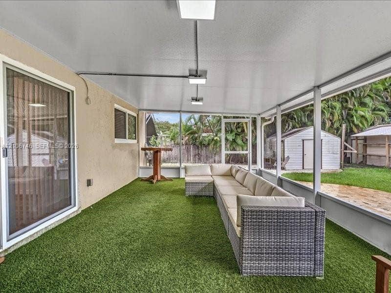 Screened-in patio featuring an artificial turf floor, a covered ceiling with integrated lighting, and access to a backyard area
