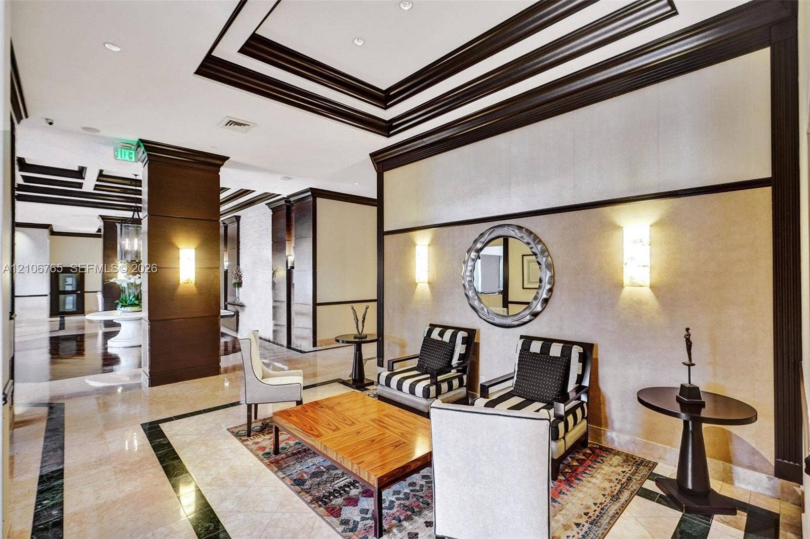 3598 Yacht Club Drive, #901, Aventura, FL 33180 Entryway, multi-tiered crown molding, recessed lighting, stone flooring with decorative dark stone borders, paneled column accents, and wall-mounted sconces.