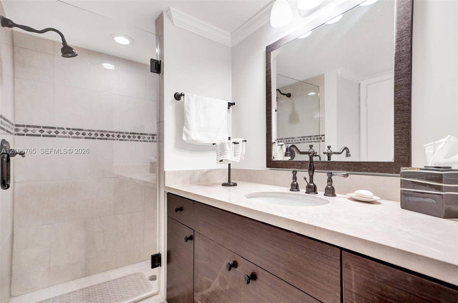 3598 Yacht Club Drive, #901, Aventura, FL 33180 Second bathroom. Custom wood-finish vanity with a stone countertop, under-mount sink, walk-in shower with a glass enclosure and decorative tile inlay.