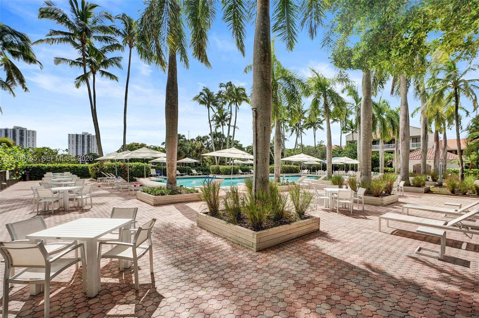 3598 Yacht Club Drive, #901, Aventura, FL 33180 Outdoor terrace featuring brick-paver hardscaping, built-in raised planters, mature palm trees, and a swimming pool