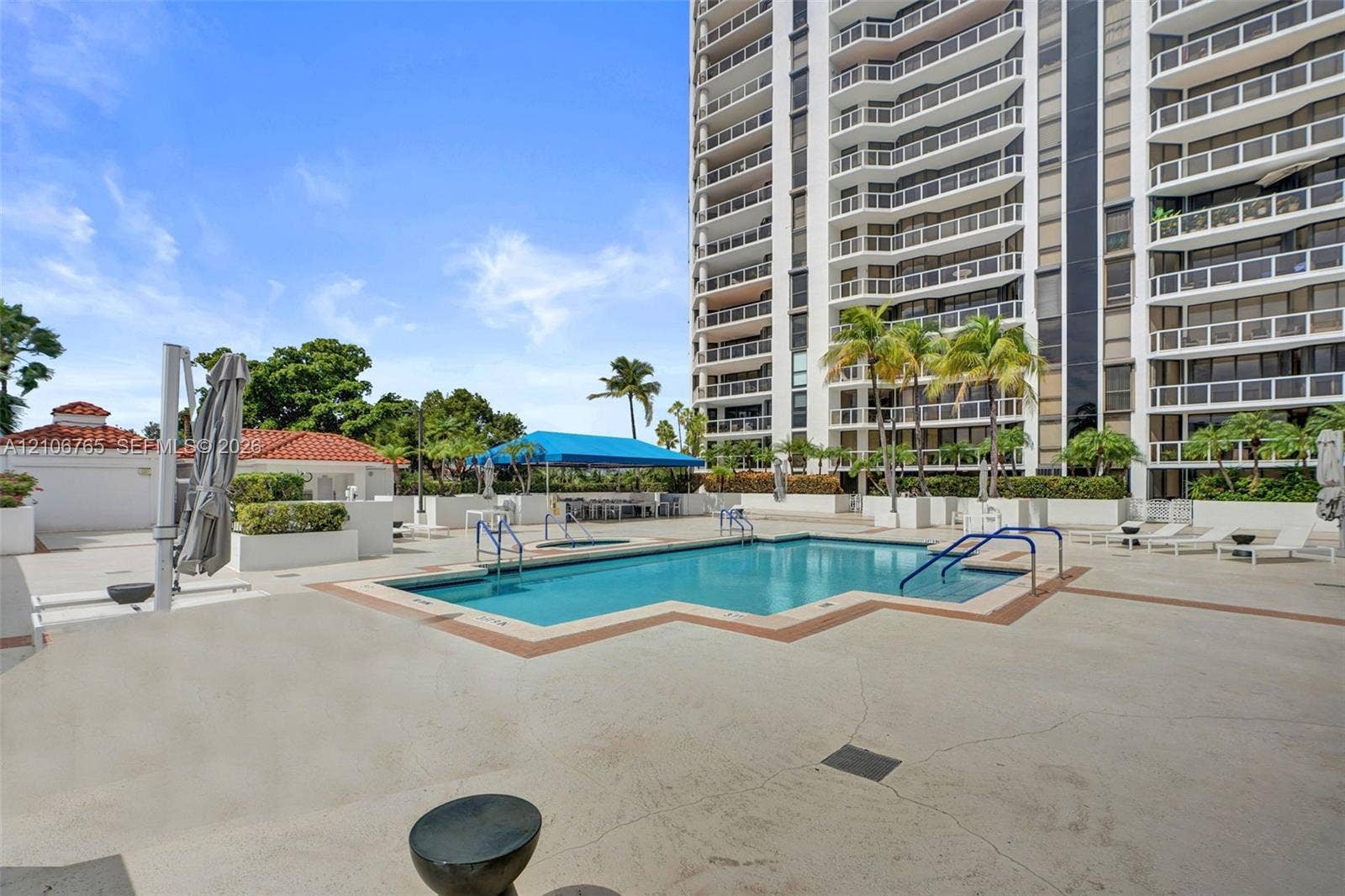 3598 Yacht Club Drive, #901, Aventura, FL 33180 Swimming pool with integrated stair entry, surrounding concrete deck, shaded cabana area, and palm tree landscaping