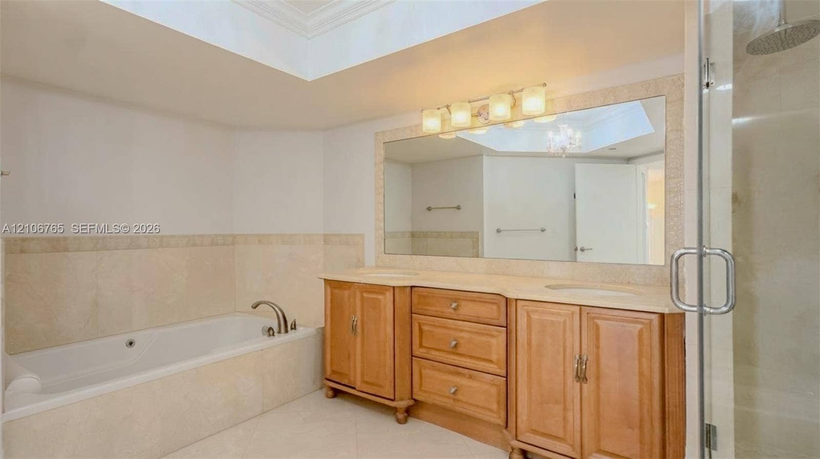 3598 Yacht Club Drive, #901, Aventura, FL 33180 Main bathroom, a soaking tub with stone surround, a dual-sink vanity with wood cabinetry, and a glass-enclosed shower
