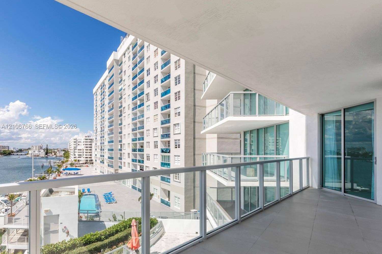 Covered balcony featuring oversized tile flooring, a glass panel railing, and aluminum framing with sliding glass door access