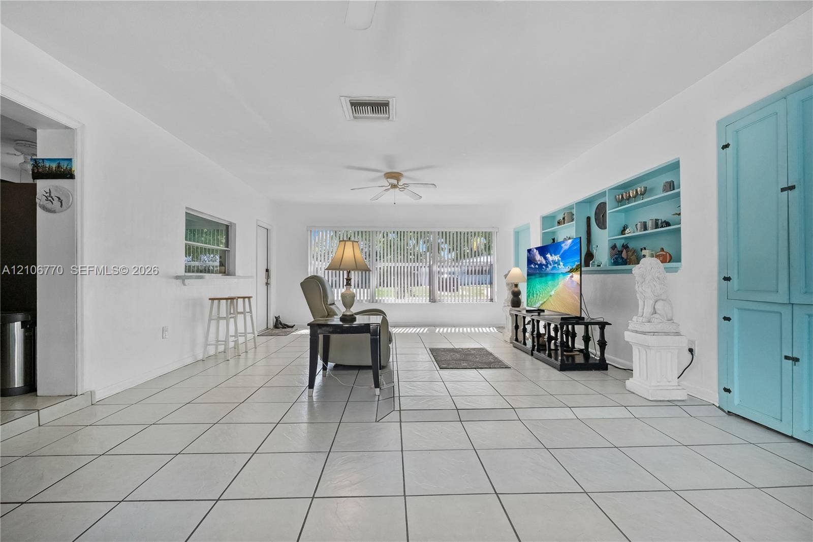 5701 SW 1st Street, Plantation, FL 33317 Living area featuring large-format ceramic tile flooring, built-in recessed shelving, integrated storage cabinetry, and a ceiling fan
