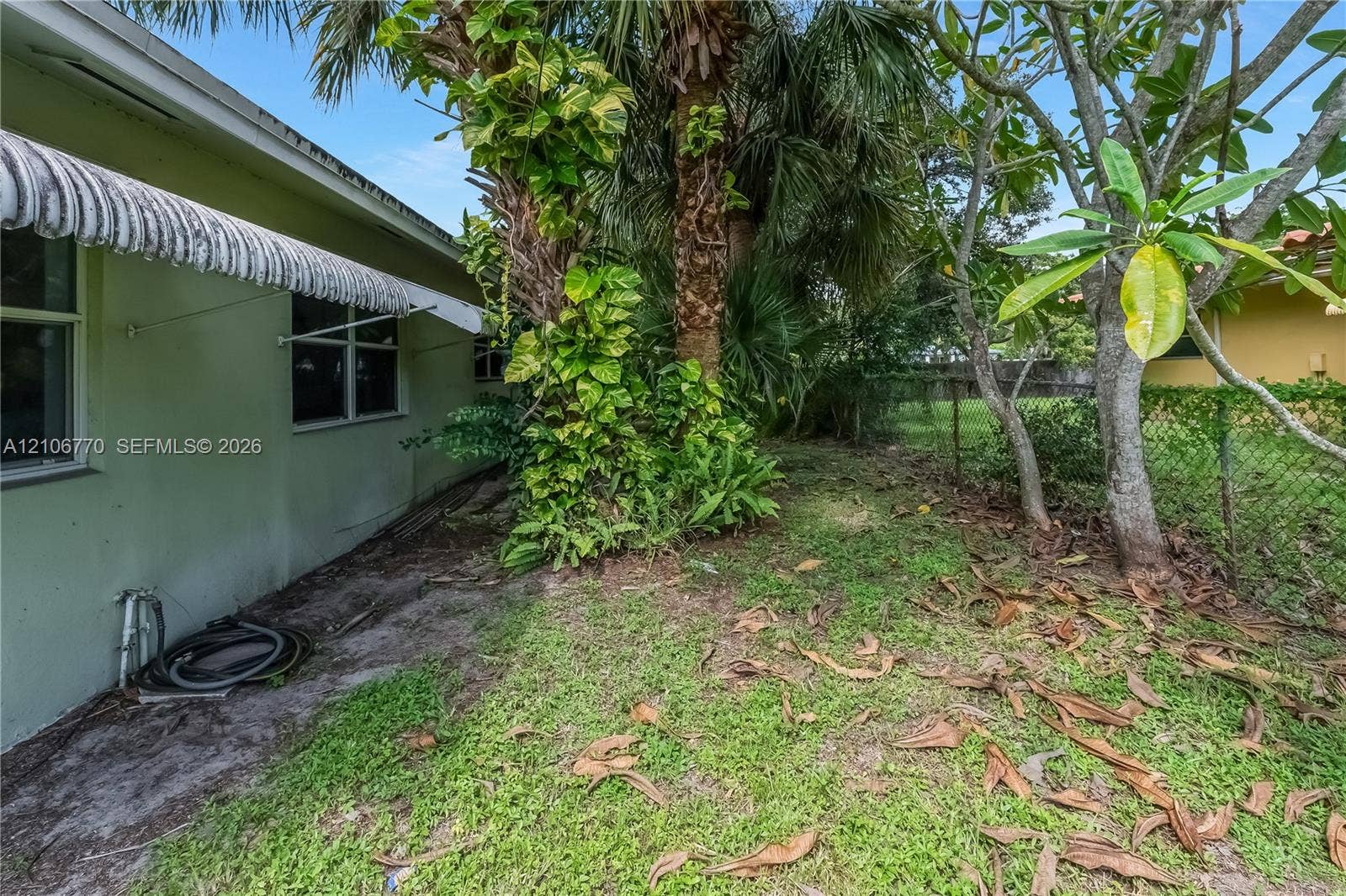 5701 SW 1st Street, Plantation, FL 33317 Exterior wall featuring fixed metal awnings, multi-pane windows, and mature palm trees