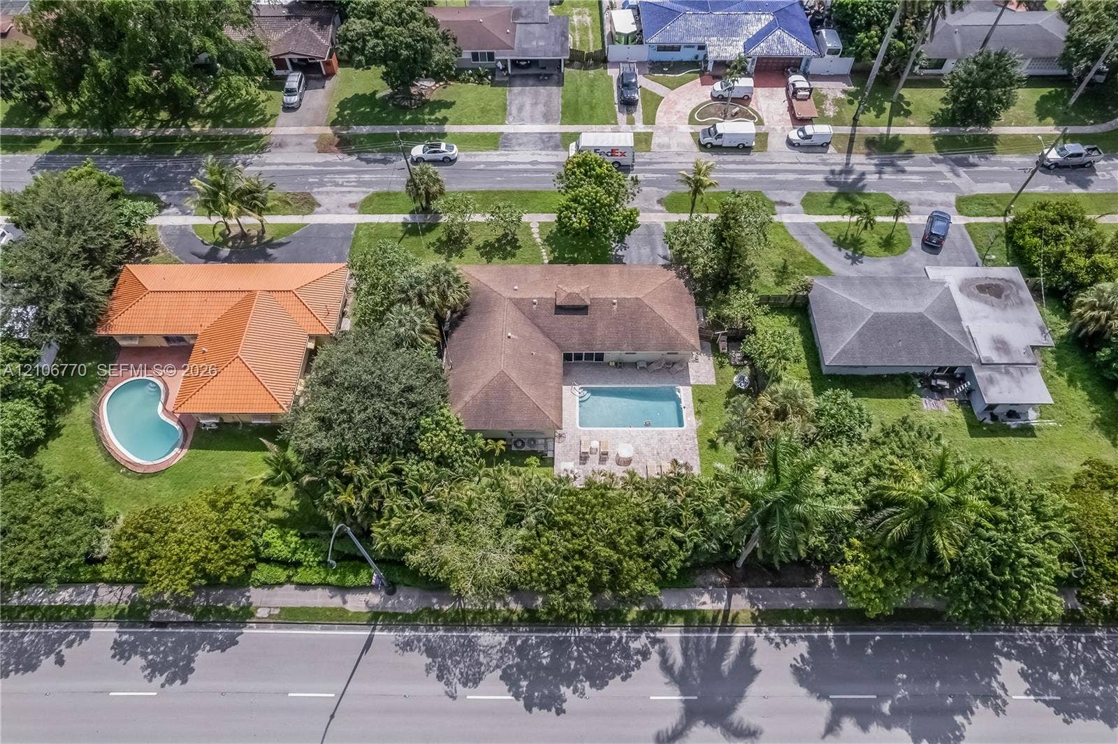 5701 SW 1st Street, Plantation, FL 33317 Aerial perspective featuring a shingled roofline, rectangular in-ground swimming pool, paved patio, and established perimeter landscaping on a lot with mature trees