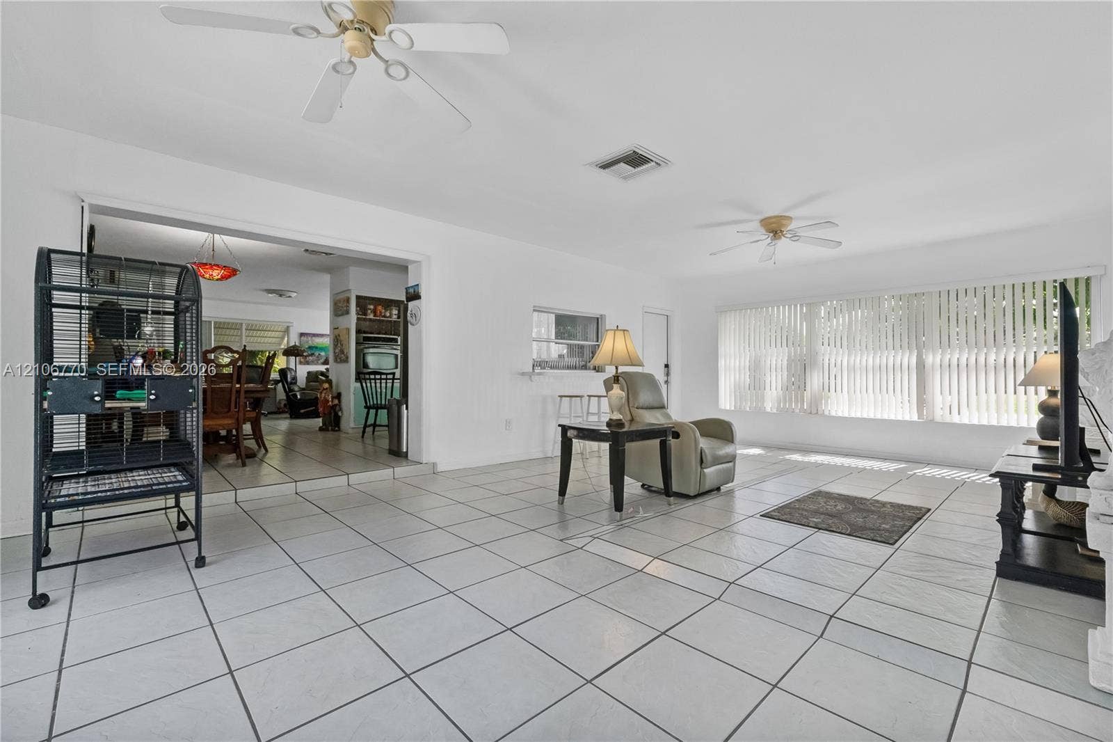 5701 SW 1st Street, Plantation, FL 33317 Living area featuring white ceramic tile flooring, dual ceiling fans, and large windows with vertical blinds