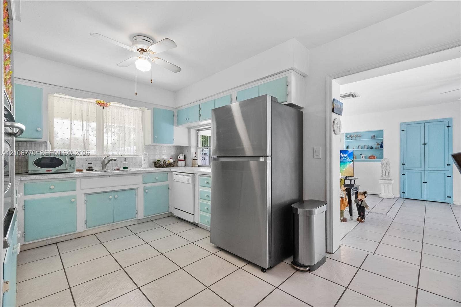 5701 SW 1st Street, Plantation, FL 33317 Kitchen featuring cabinetry with light blue finish, stainless steel refrigerator, white dishwasher, tile flooring, and ceiling fan with integrated lighting