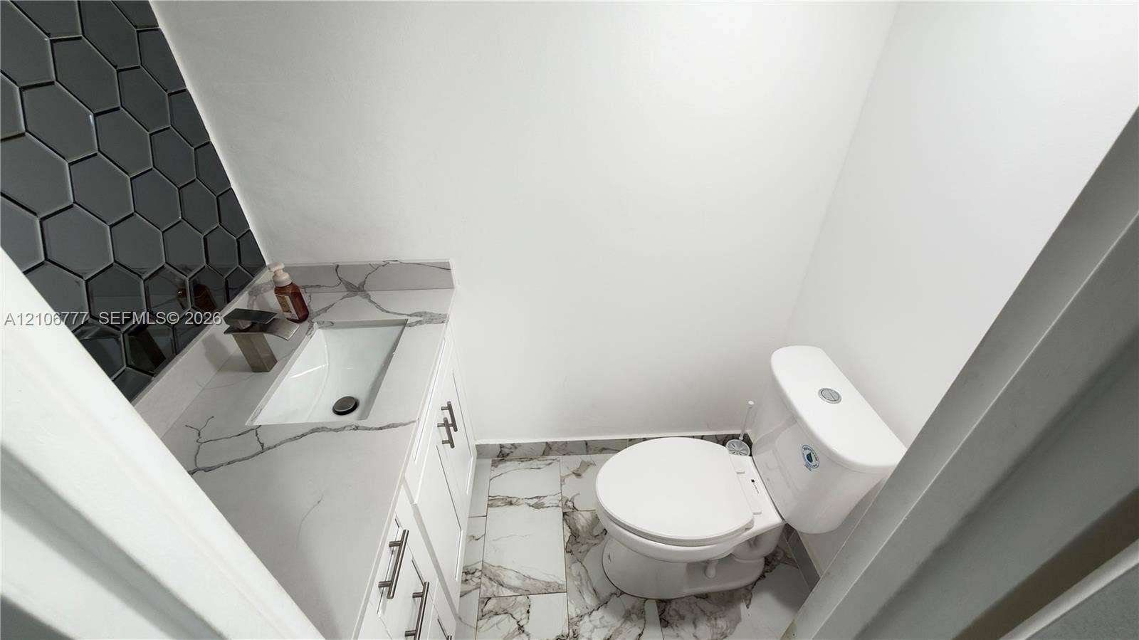 1810 SW 81st Avenue, #2200, North Lauderdale, North Lauderdale, FL 33068 White vanity with a veined stone-finish countertop, rectangular under-mount sink, matte-finish faucet, charcoal hexagon-tile backsplash, and large-format porcelain tile flooring