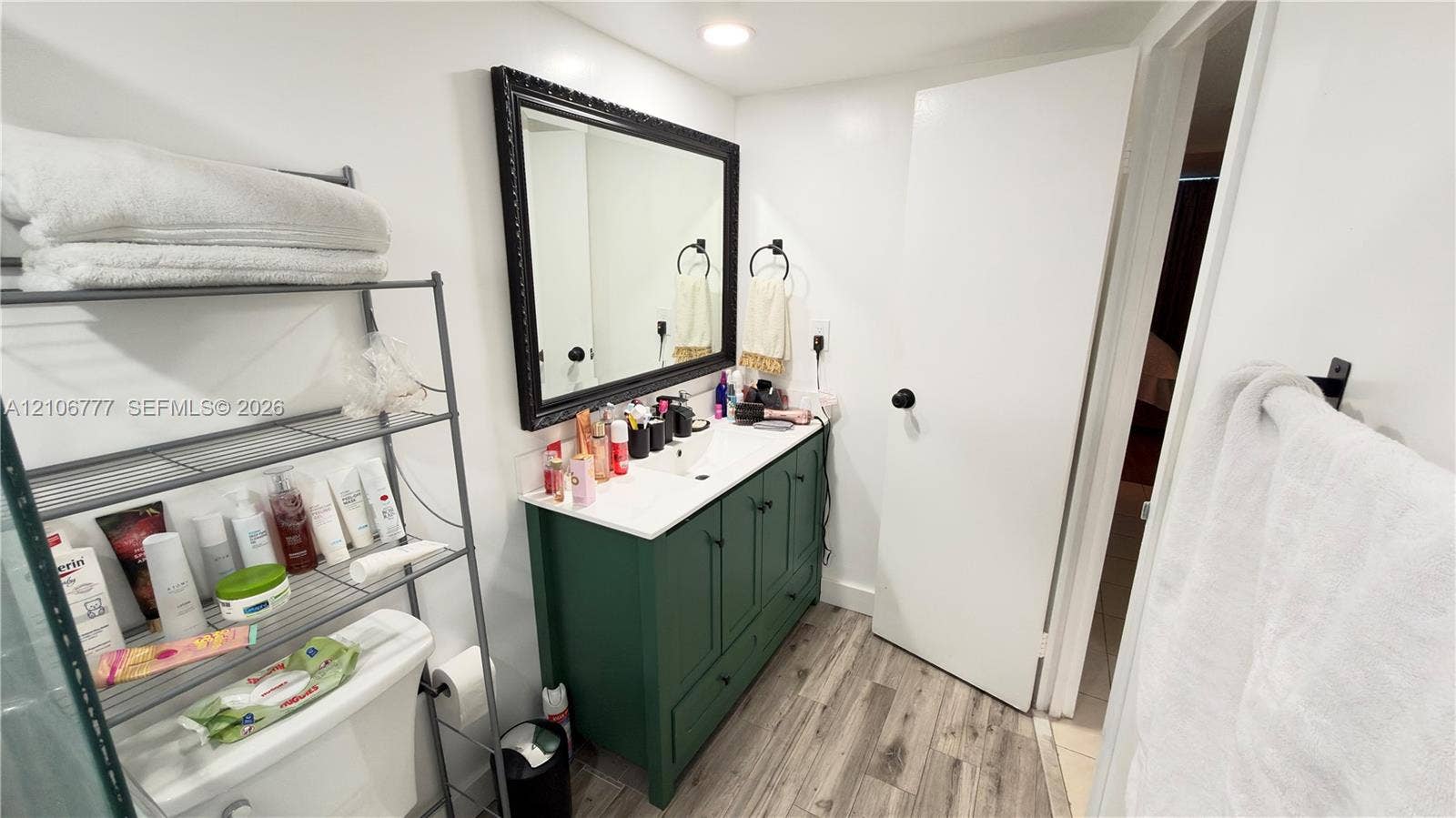 1810 SW 81st Avenue, #2200, North Lauderdale, North Lauderdale, FL 33068 Bathroom vanity featuring a green cabinetry base, white countertop, integrated basin, and black-framed mirror, complemented by wood-finish flooring