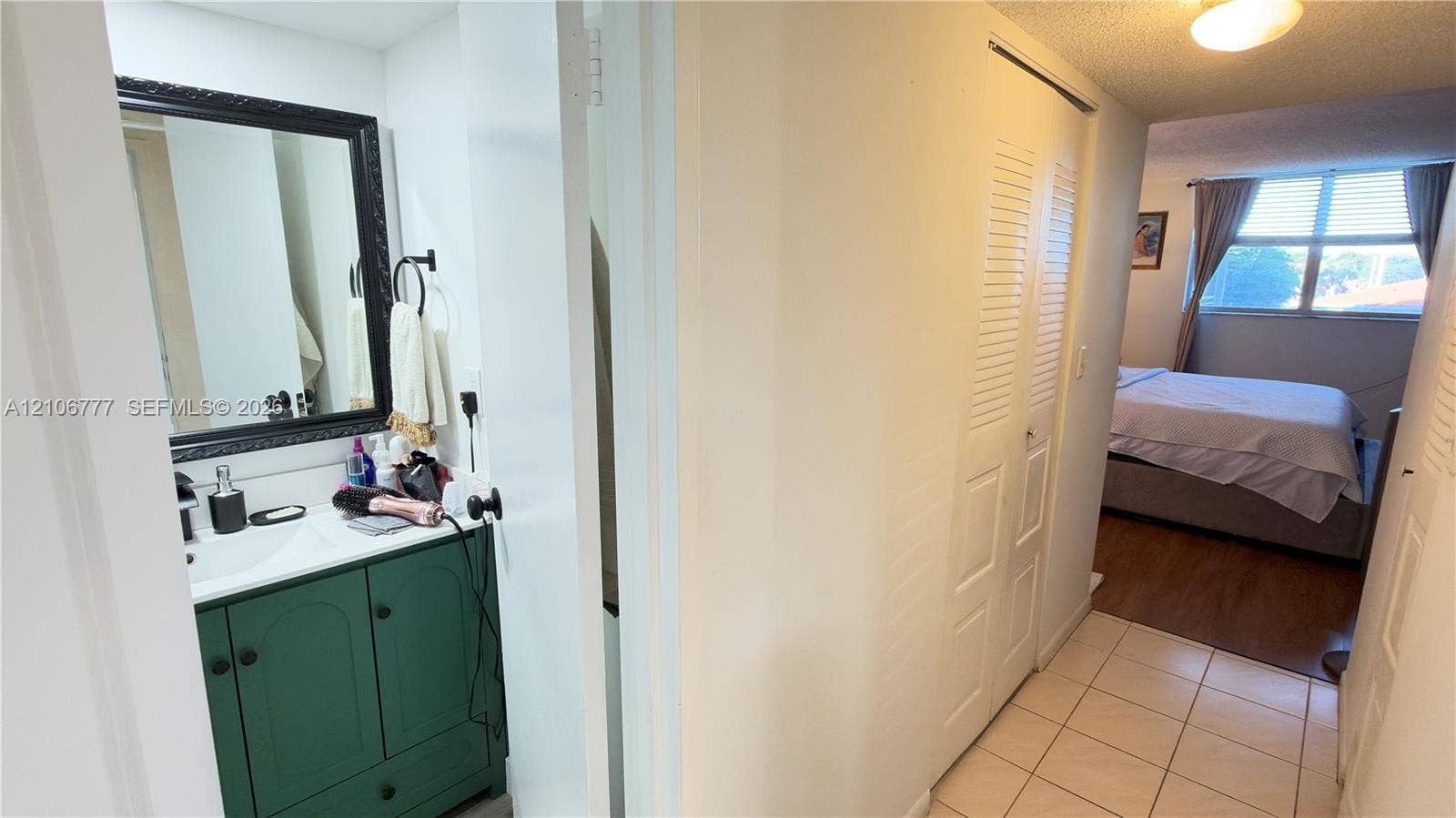 1810 SW 81st Avenue, #2200, North Lauderdale, North Lauderdale, FL 33068 Bathroom vanity featuring a green cabinetry base, white countertop with integrated sink, and dark-toned framed mirror, complemented by ceramic floor tiling and louvered closet doors
