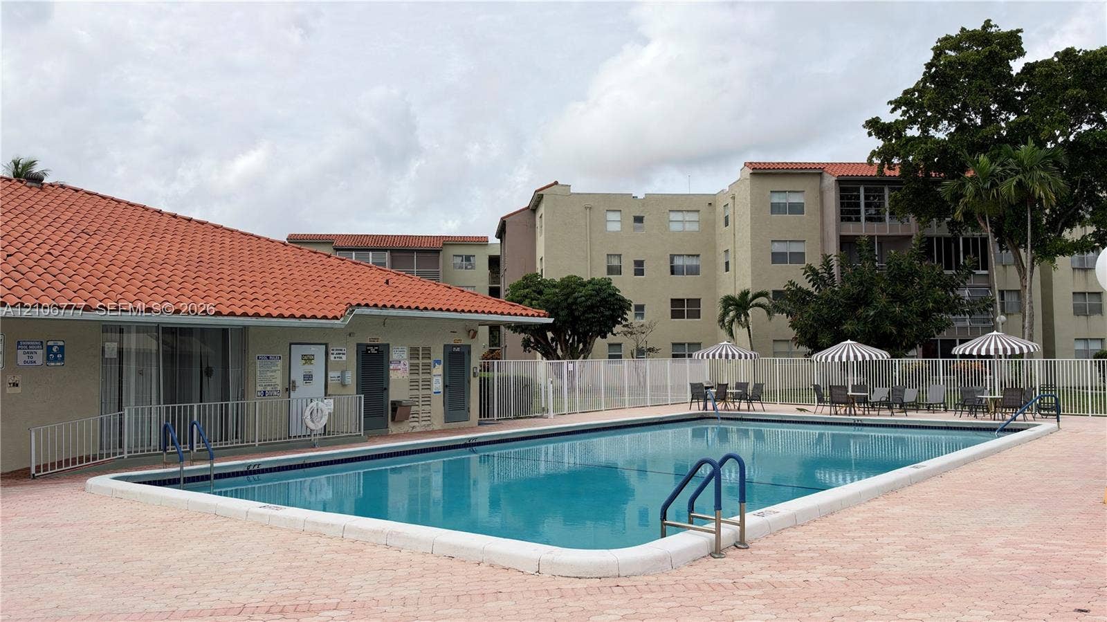 1810 SW 81st Avenue, #2200, North Lauderdale, North Lauderdale, FL 33068 In-ground swimming pool featuring a concrete deck, metal safety fencing, and a red tile roof clubhouse