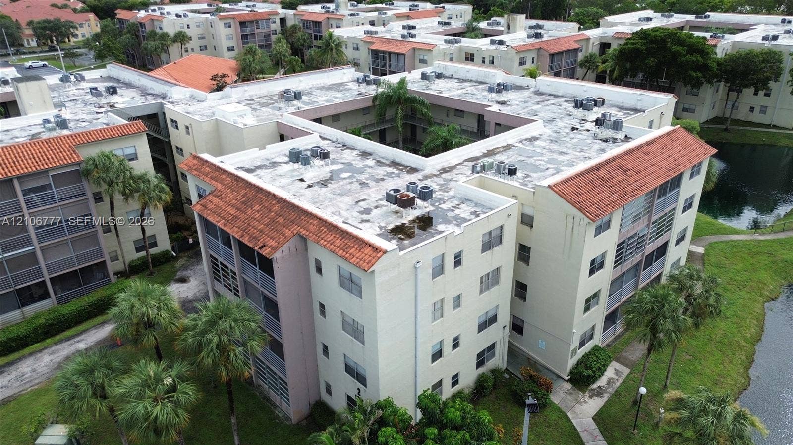 1810 SW 81st Avenue, #2200, North Lauderdale, North Lauderdale, FL 33068 Multi-story residential complex featuring barrel tile roof accents, screened balconies, and mature palm landscaping situated on a pond