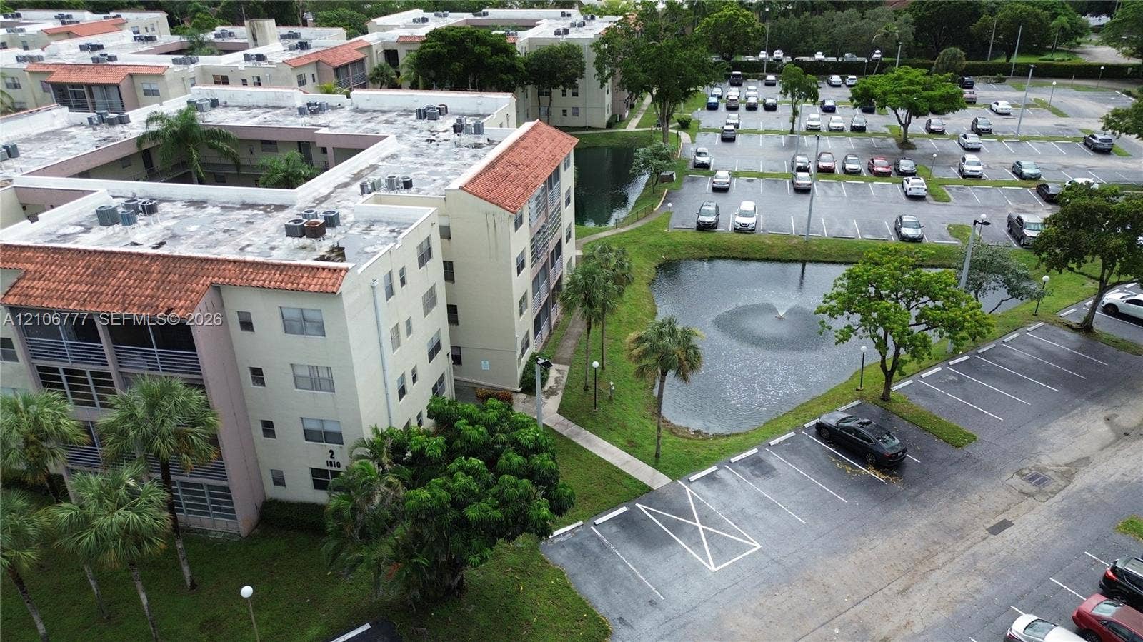 1810 SW 81st Avenue, #2200, North Lauderdale, North Lauderdale, FL 33068 Multi-story residential building featuring a terracotta tile roof, balcony enclosures, landscaped grounds, a central fountain, and dedicated parking areas