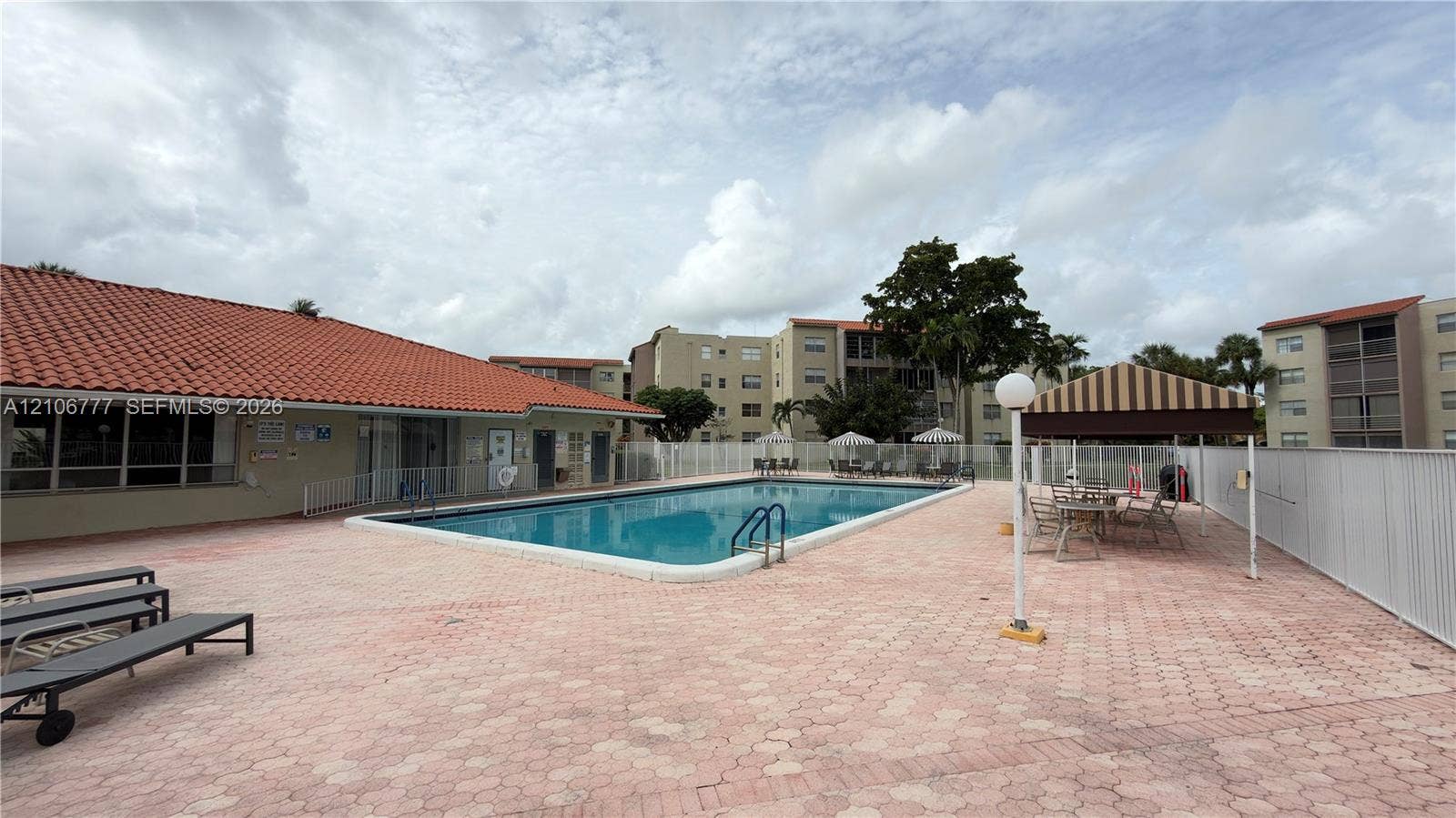 1810 SW 81st Avenue, #2200, North Lauderdale, North Lauderdale, FL 33068 Rectangular swimming pool featuring a concrete deck, red tile roofing, and a metal-framed shaded pavilion