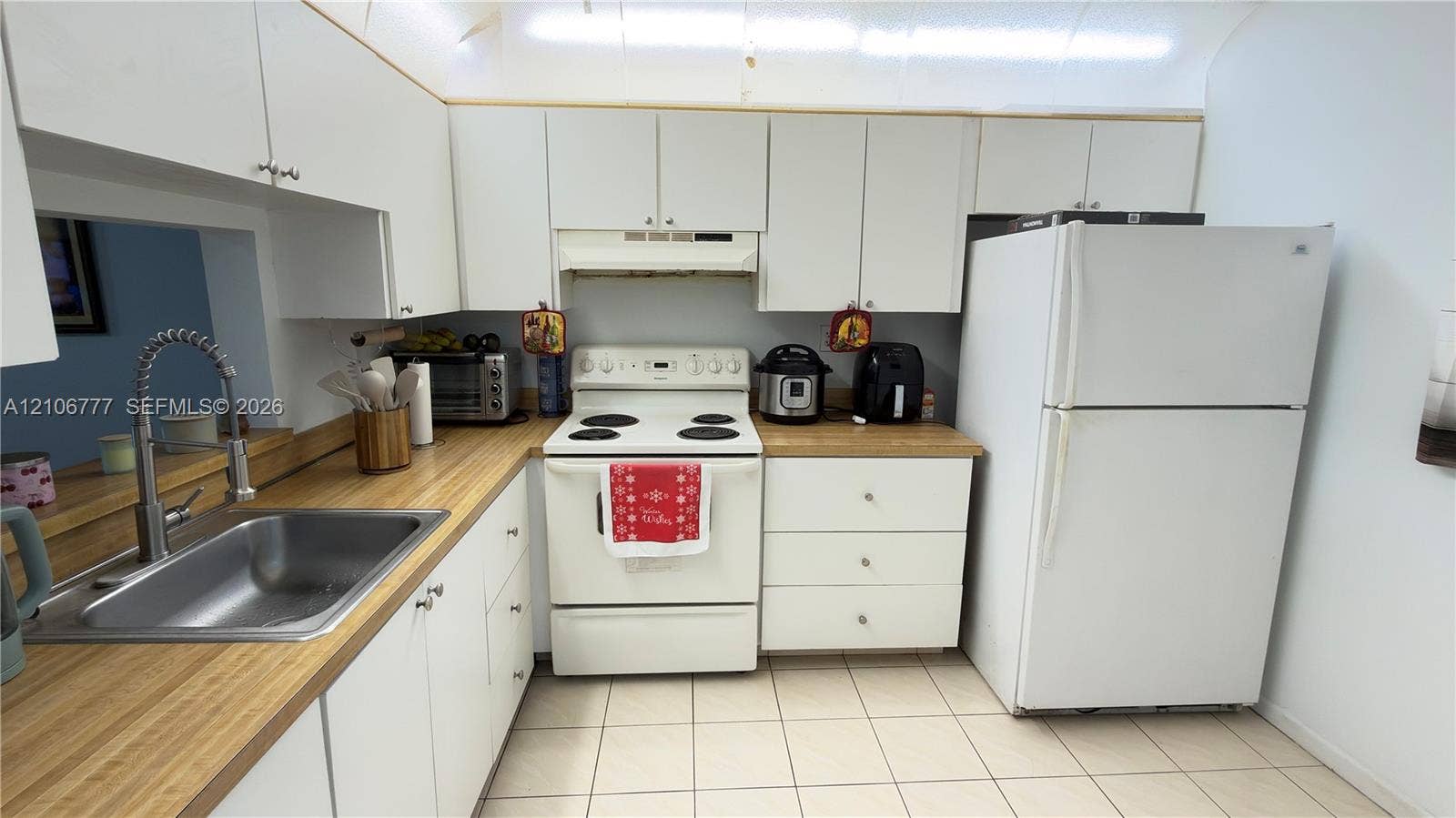 1810 SW 81st Avenue, #2200, North Lauderdale, North Lauderdale, FL 33068 Kitchen featuring white cabinetry, butcher-block style countertops, tile flooring, built-in range hood, and stainless steel sink with high-arc pull-down faucet