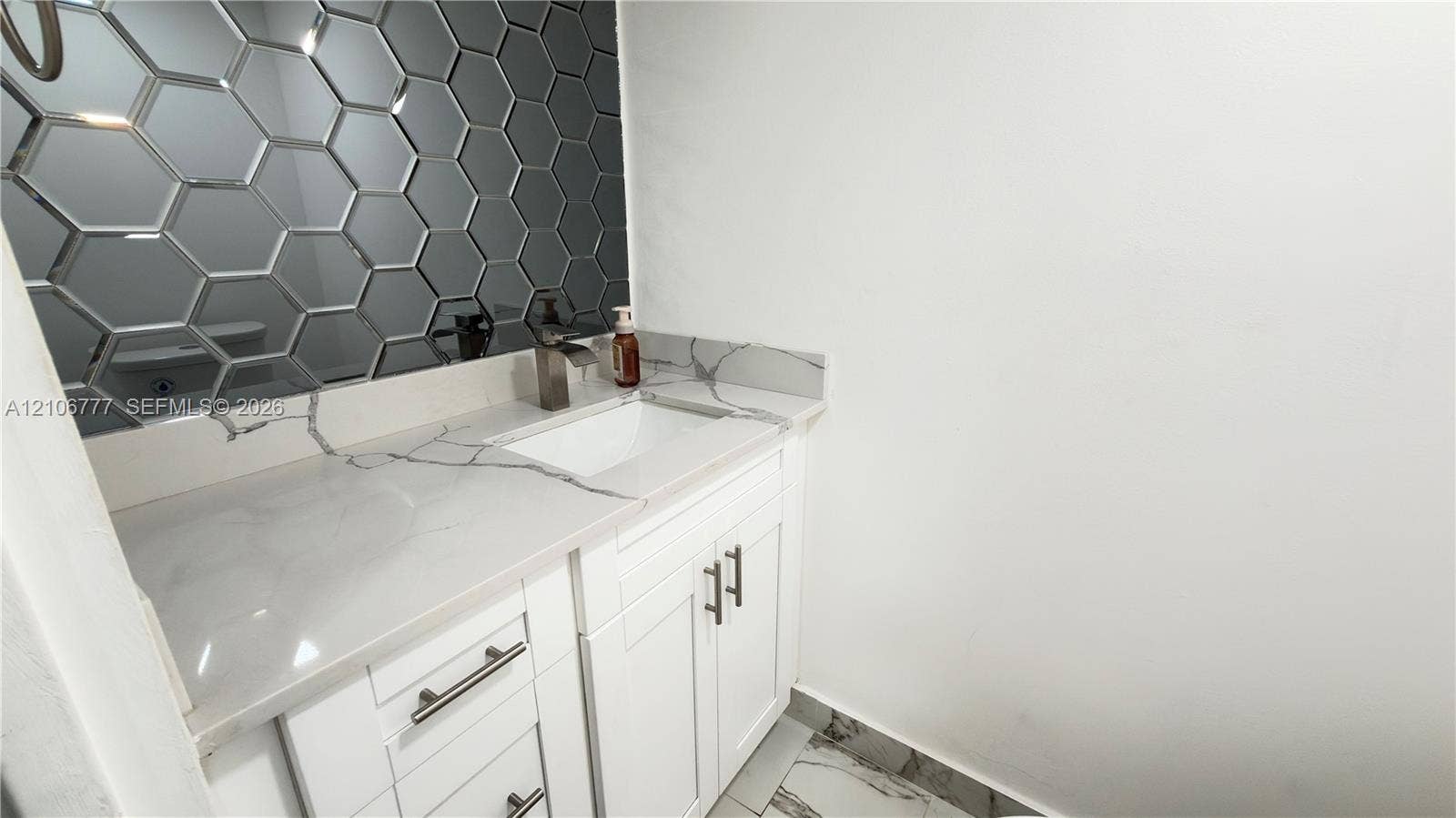 1810 SW 81st Avenue, #2200, North Lauderdale, North Lauderdale, FL 33068 Vanity with white cabinetry, stone-surface countertop, integrated rectangular sink, metallic faucet, and decorative hexagonal mirror tiling