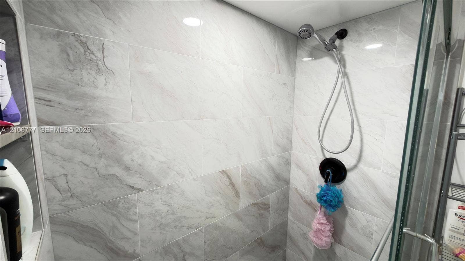 1810 SW 81st Avenue, #2200, North Lauderdale, North Lauderdale, FL 33068 Walk-in shower featuring large-format stone-patterned wall tile, a handheld showerhead, matte black faucet trim, and a glass enclosure