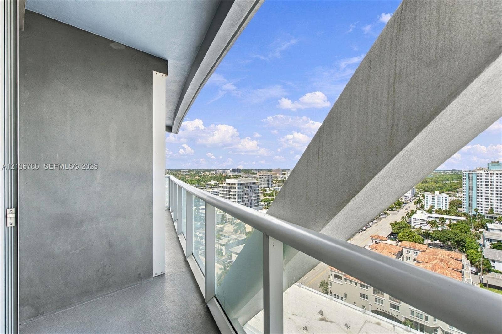 Private balcony featuring a concrete floor, glass panel railing, and structural steel support elements