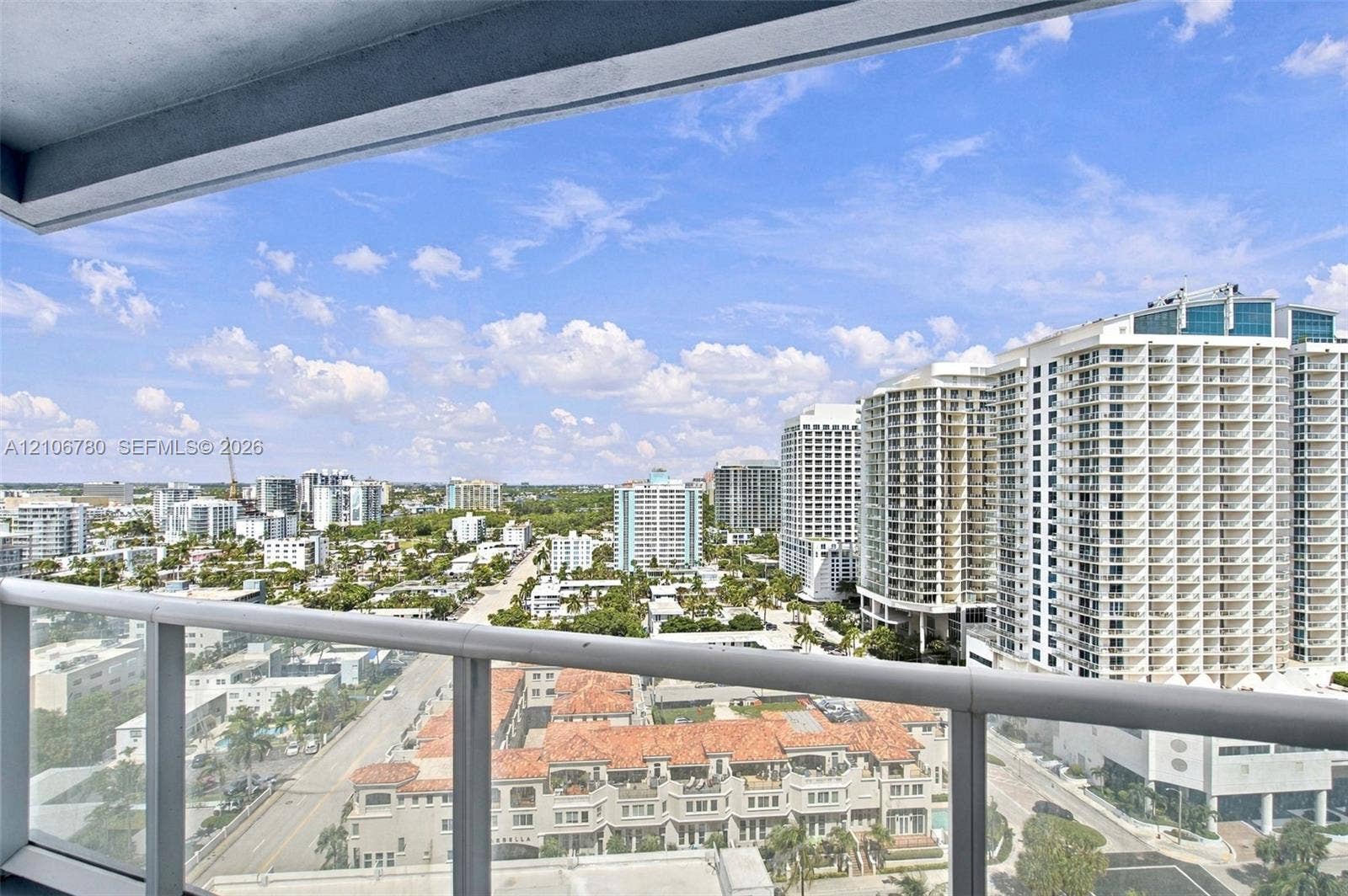 Elevated balcony featuring a glass and metal railing overlooking a cityscape