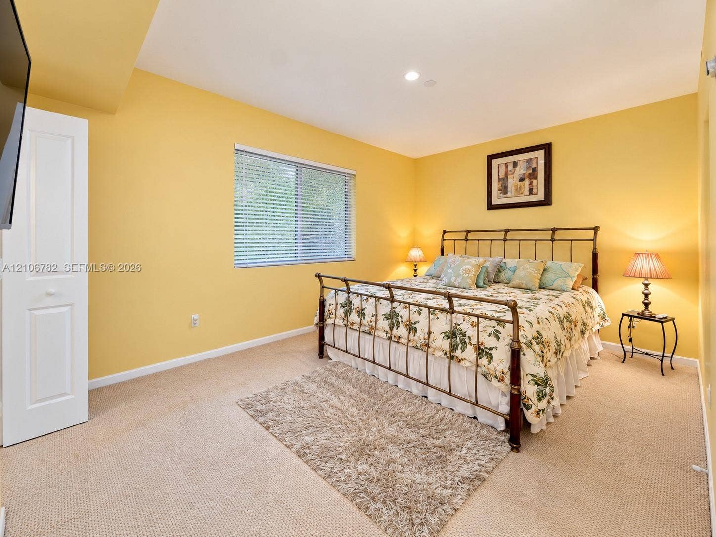 Neutral carpeting, recessed lighting, and a single-panel closet door