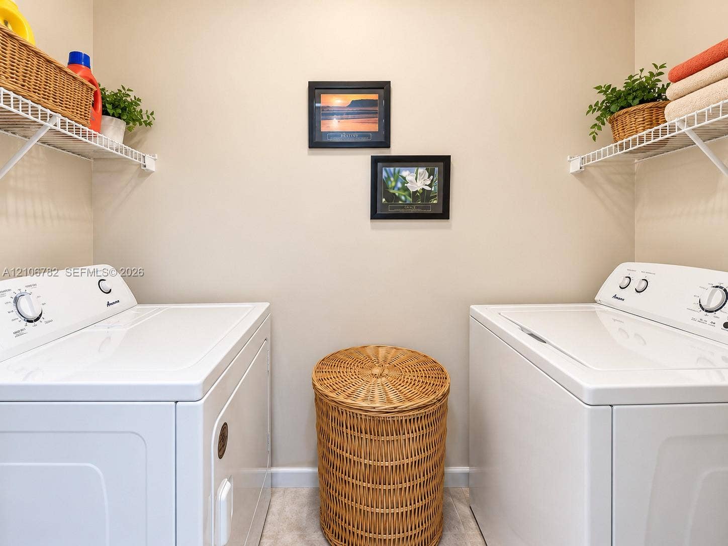 Laundry area featuring dual white appliances and white wire shelving