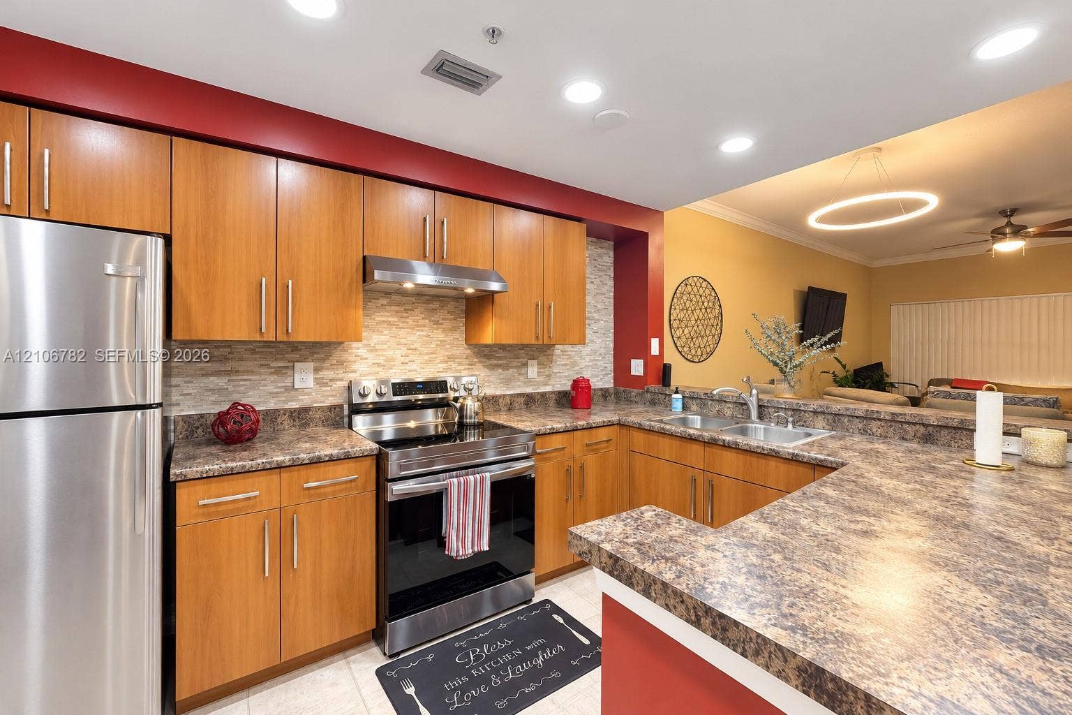 Kitchen featuring wood-finish cabinetry, stone-patterned laminate countertops, stainless steel appliances, a textured stone-tile backsplash, and recessed lighting