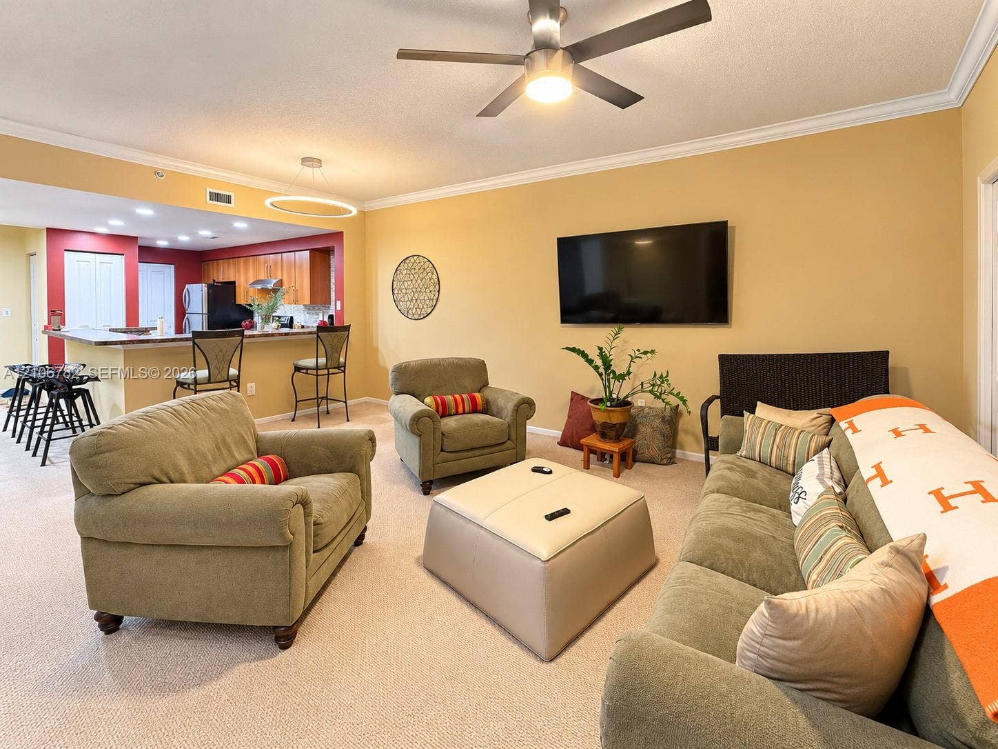 Open-concept floor plan featuring a kitchen breakfast bar, recessed lighting, crown molding, and a ceiling fan