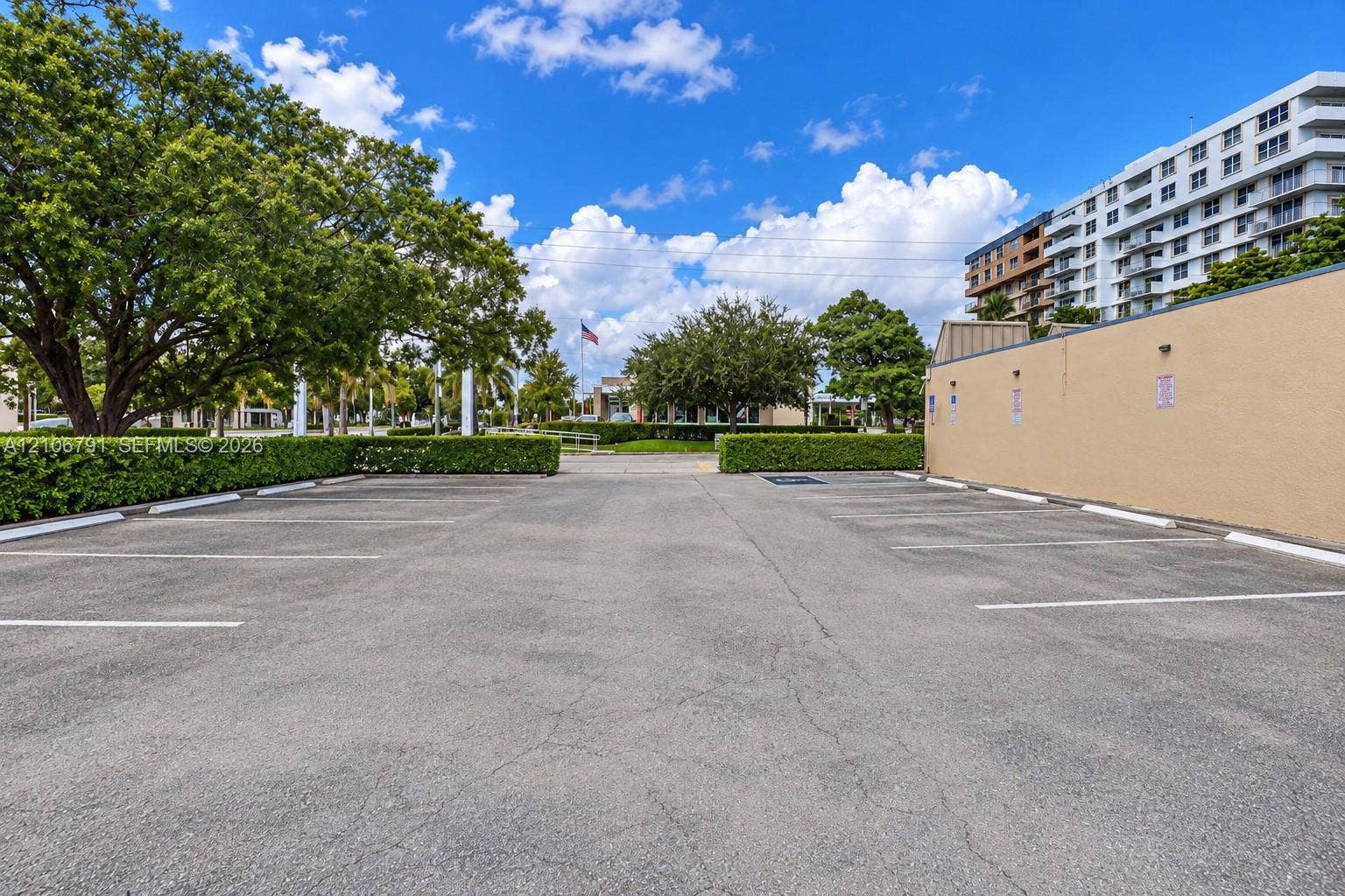 1684 SE 10th Avenue, Fort Lauderdale, Fort Lauderdale, FL 33316 Paved surface parking area featuring painted stall markers, landscaped hedges, and mature trees
