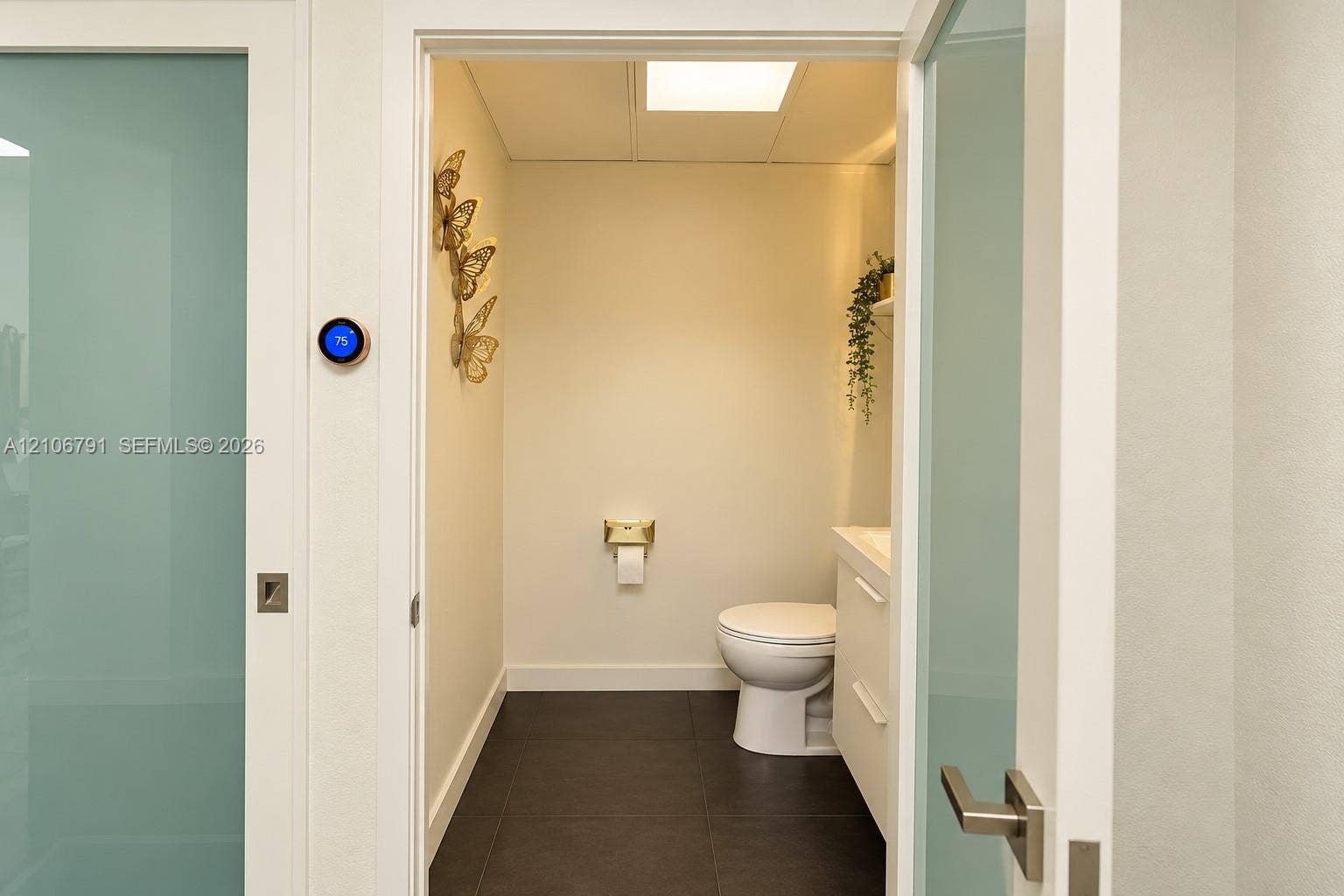 1684 SE 10th Avenue, Fort Lauderdale, Fort Lauderdale, FL 33316 Frosted glass paneled doors with brushed metal hardware, dark tile flooring, wall-mounted smart thermostat, and a minimalist vanity