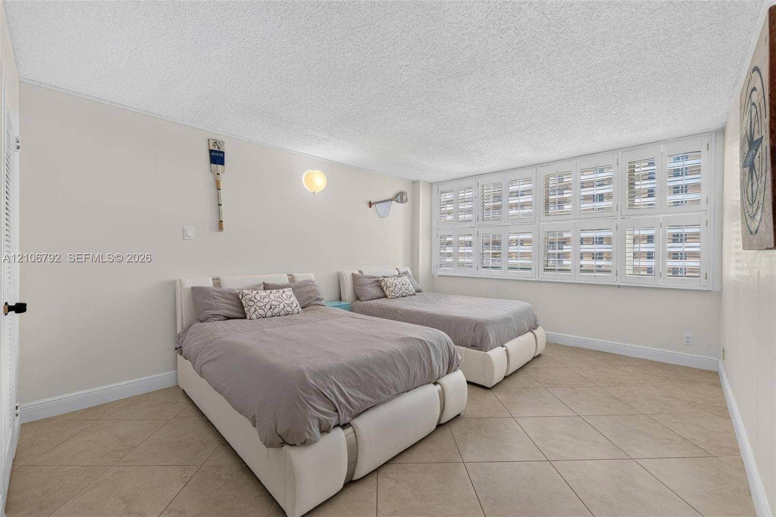 2030 S Ocean Drive, #723, Hallandale Beach, FL 33009 Neutral interior space featuring large-format diagonal tile flooring, white plantation shutters, and a wall-mounted light fixture