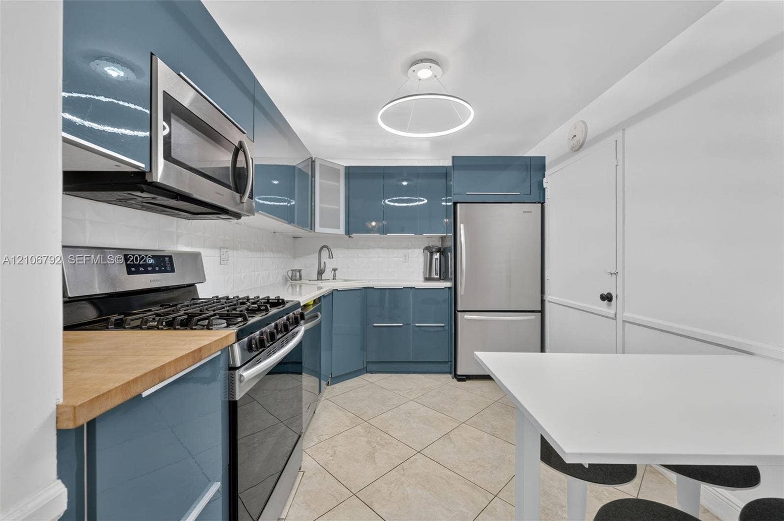2030 S Ocean Drive, #723, Hallandale Beach, FL 33009 Glossy blue cabinetry featuring flat-panel doors, stainless steel appliances, butcher block countertops, white tiled backsplash, and circular LED overhead lighting