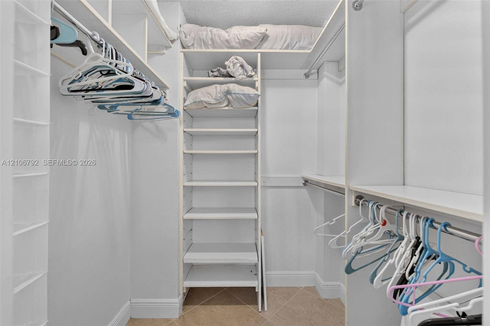 2030 S Ocean Drive, #723, Hallandale Beach, FL 33009 Walk-in closet featuring white built-in shelving, multiple hanging rods, and tile flooring