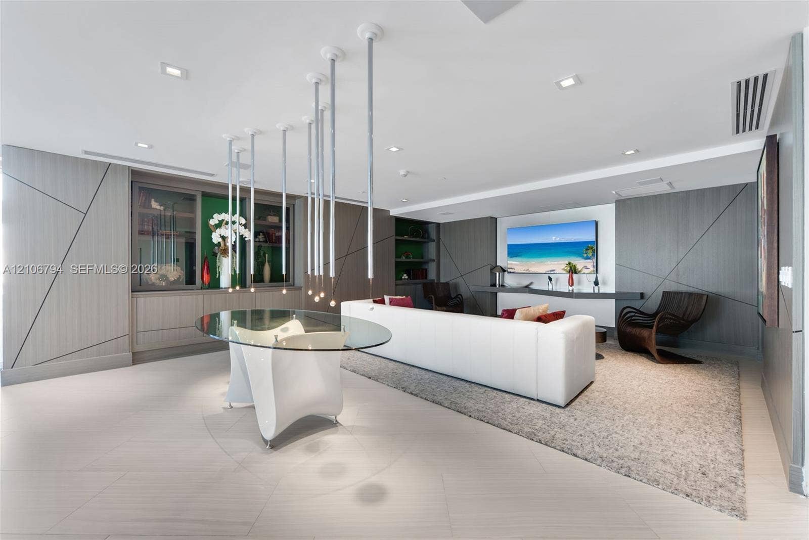 Open-concept area featuring large-format tile flooring, custom wall paneling with geometric detailing, built-in cabinetry, and a tiered pendant lighting fixture