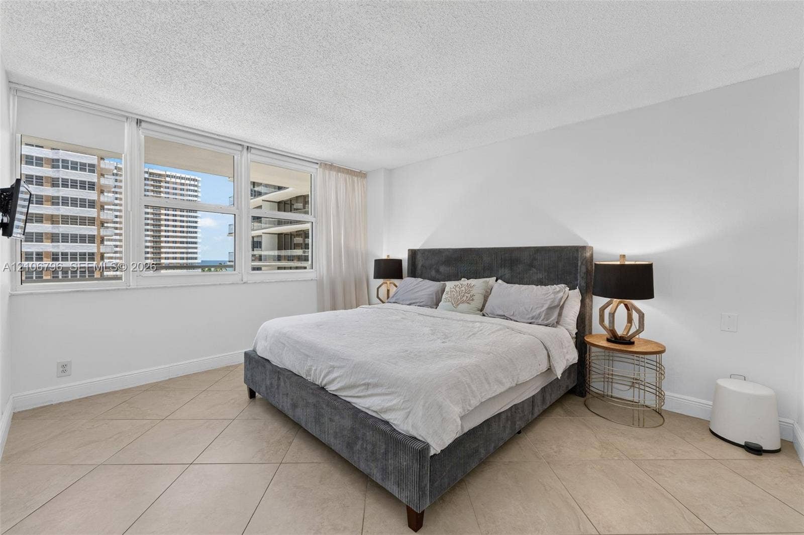 Large-format ceramic tile flooring, expansive floor-to-ceiling windows, and textured ceiling finish